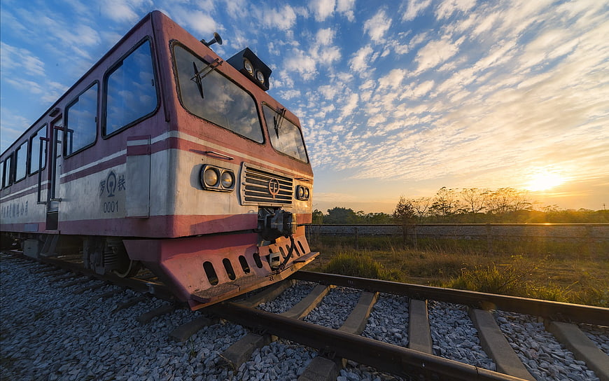 Vintage red train on tracks at sunset with blue sky
