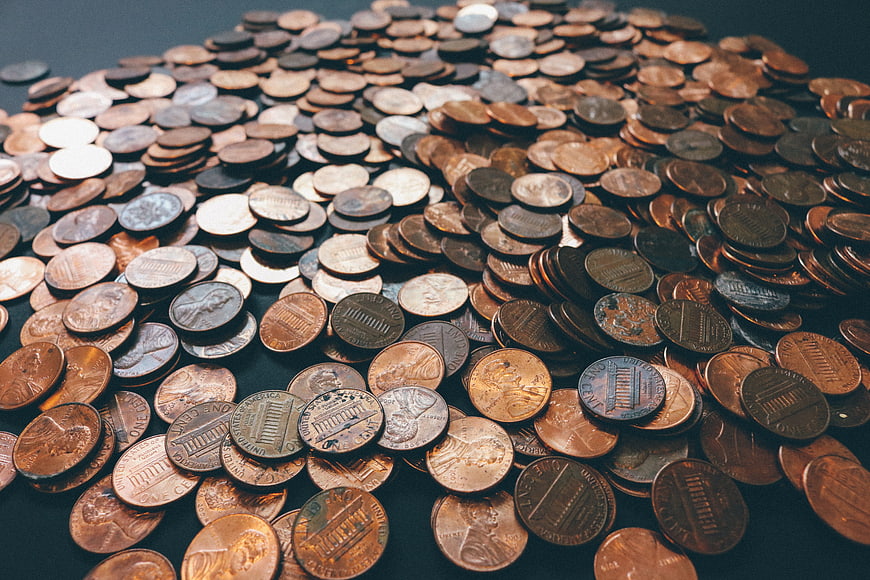 Pile of US Pennies and Coins on Dark Surface