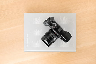Black Fujifilm Camera on White Book Flat Lay