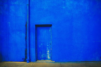 Vibrant Blue Wall with Weathered Door and Drainpipe