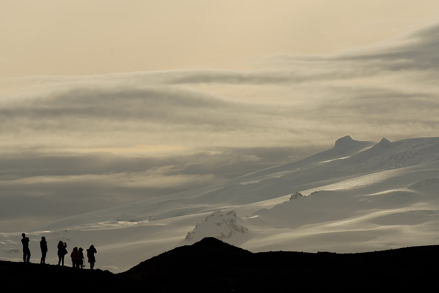 Silhouetted Hikers on Snowy Mountain Ridge at Dusk