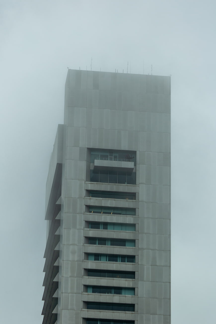 Tall modern skyscraper disappearing into thick fog