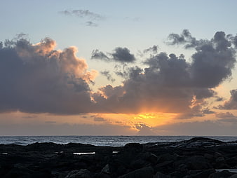 Dramatic sunset over rocky ocean coast with golden clouds