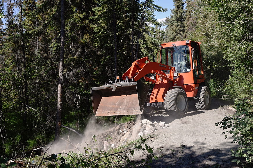 Orange Wheel Loader Moving Rocks on Forest Road