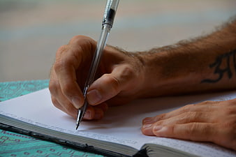 Close-up of Man Writing in Notebook with Pen