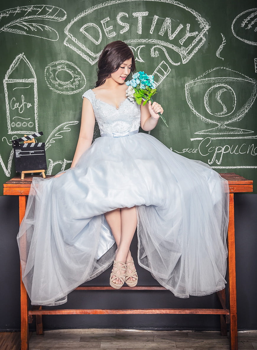 Bride in Blue Gown Sitting on Bench with Chalkboard Background