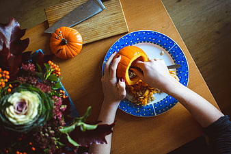 Top View of Hands Scooping Pumpkin Seeds on Blue Plate
