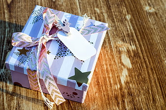 Wrapped Gift Box with Ribbon and Tag on Wooden Table