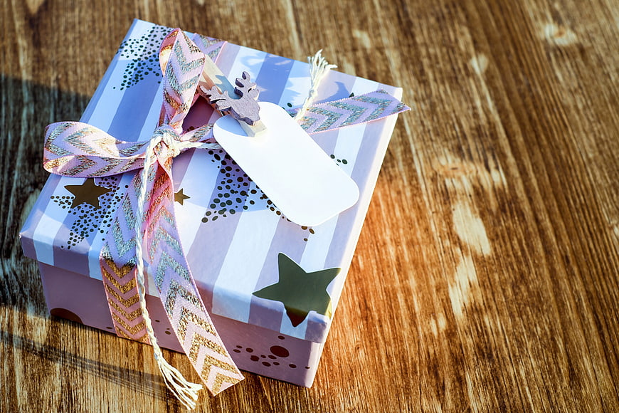 Wrapped Gift Box with Ribbon and Tag on Wooden Table