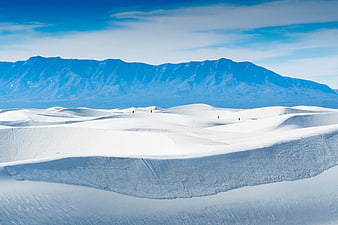 White sand dunes with mountains and tiny hikers