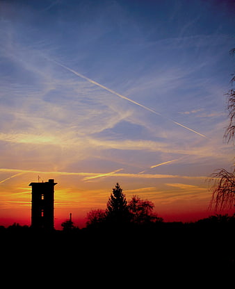 Silhouette of old fire station tower against dramatic sunset sky