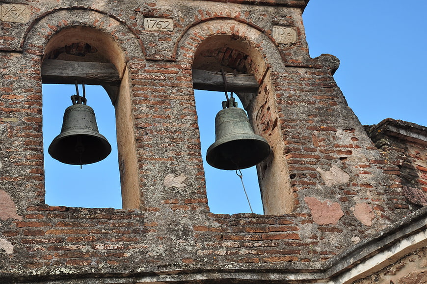 Ancient brick bell tower with two bells against blue sky