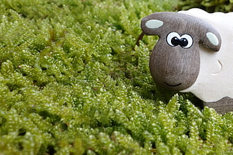 Cute wooden toy sheep on green moss background