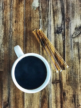 Top View of Black Coffee Cup with Sugar Packets on Rustic Wood