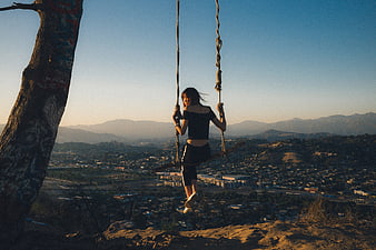 Woman on Rope Swing at Sunset Over City