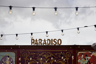 Paradiso sign with string lights against cloudy sky