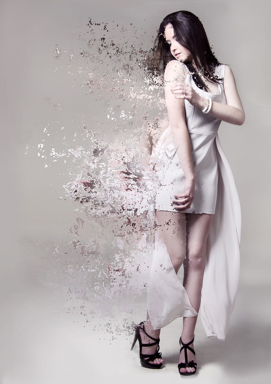 Young woman in white dress with digital dissolve effect