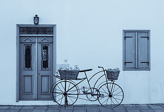 Vintage bicycle with baskets against a blue traditional house facade