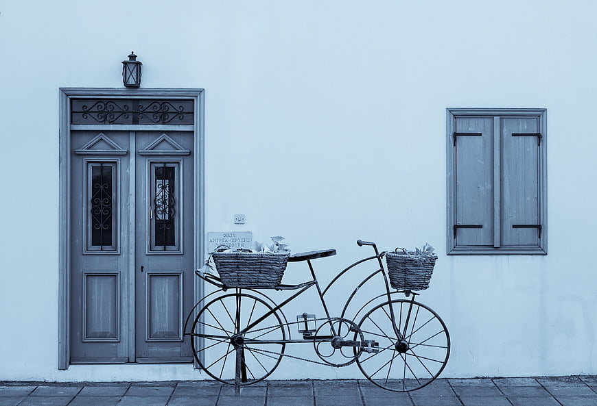 Vintage bicycle with baskets against a blue traditional house facade