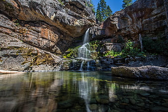 Serene waterfall cascading into a clear pool in a rocky canyon