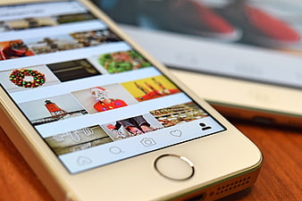 Gold smartphone displaying Instagram feed on wooden table