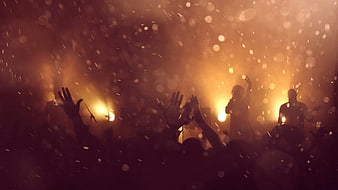 Concert Crowd Silhouettes With Raised Hands And Golden Stage Lights