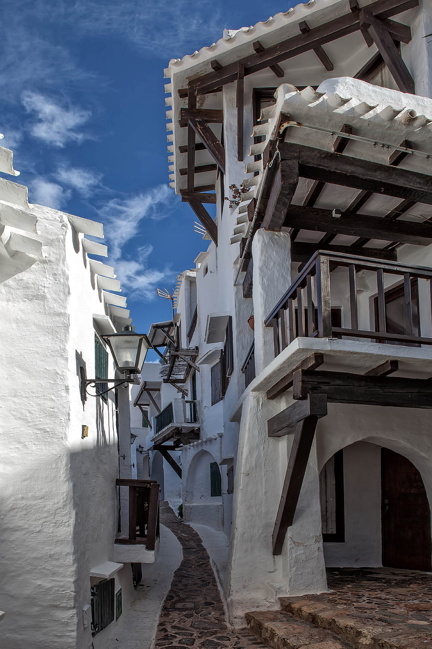 Narrow cobblestone alley in traditional Greek village with white buildings