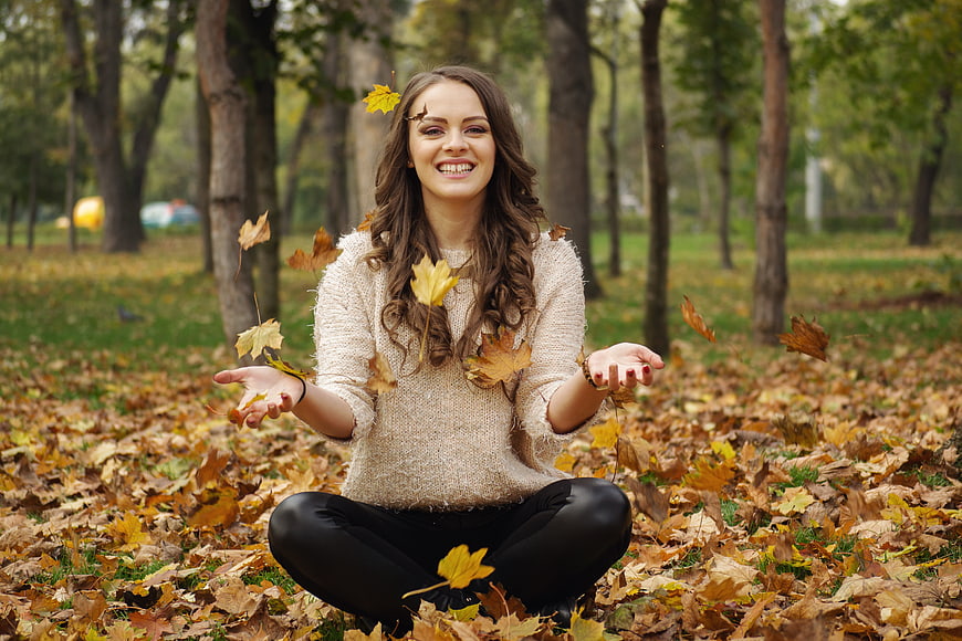 Happy Woman Throwing Autumn Leaves in Park
