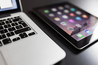Close-up of MacBook and iPad on a dark desk