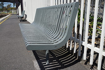 Empty gray metal bench at sunny train station platform
