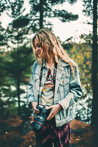 Young female photographer holding camera in forest
