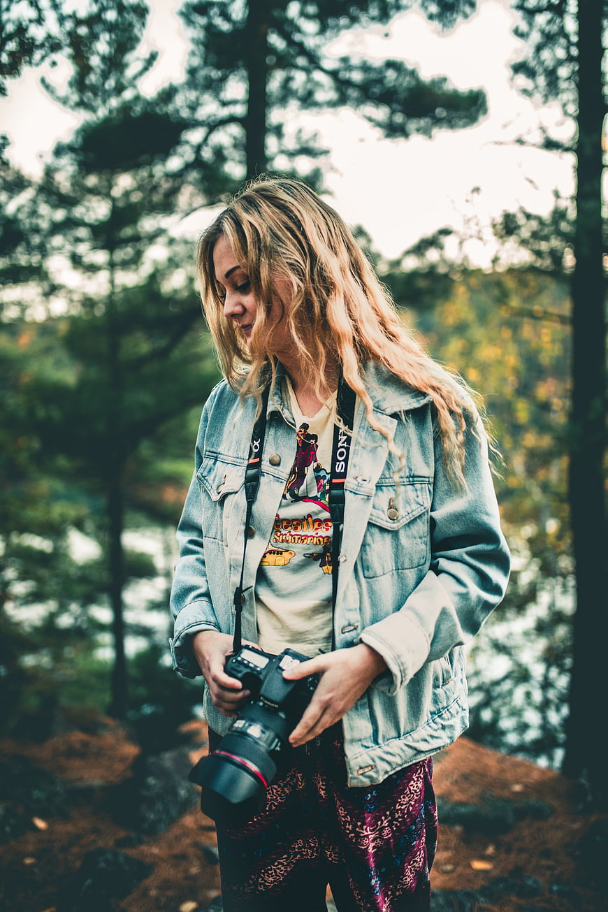 Young female photographer holding camera in forest