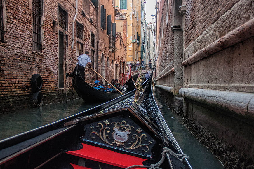 Gondola in narrow Venetian canal with brick buildings