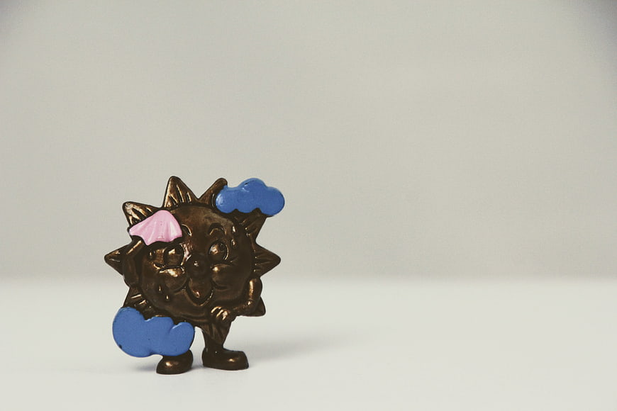 Bronze Sun Figurine with Blue Clouds on White Background