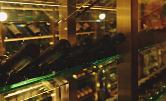 Wine bottles on glass shelves in a dimly lit cellar