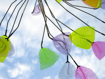 Colorful glass leaf mobile sculpture against blue sky