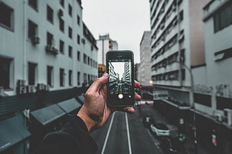 Hand holding smartphone taking photo of city street