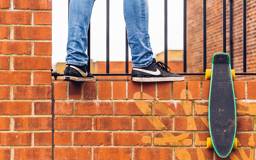 Skateboarder legs on brick wall with longboard
