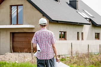 Architect with blueprints inspecting new house construction