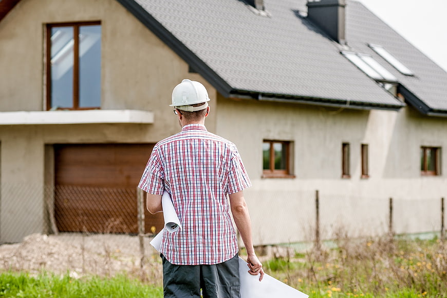 Architect with blueprints inspecting new house construction