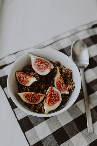 Overhead view of granola bowl with fresh figs on checkered cloth