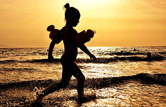 Silhouette of Girl Running in Ocean Waves at Sunset