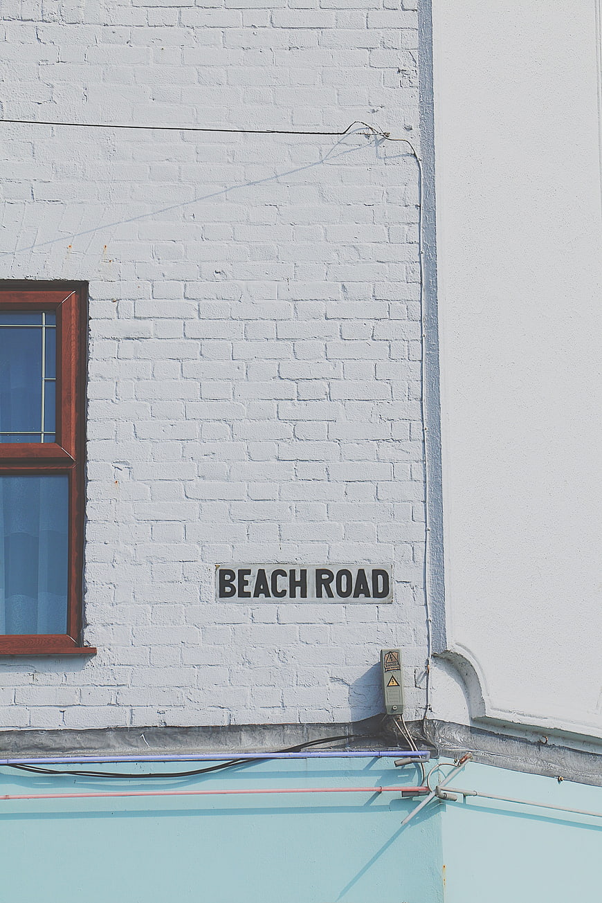 Beach Road Sign on White Brick Wall with Window