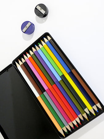 Flat lay of colorful pencils in a black tin box with sharpeners