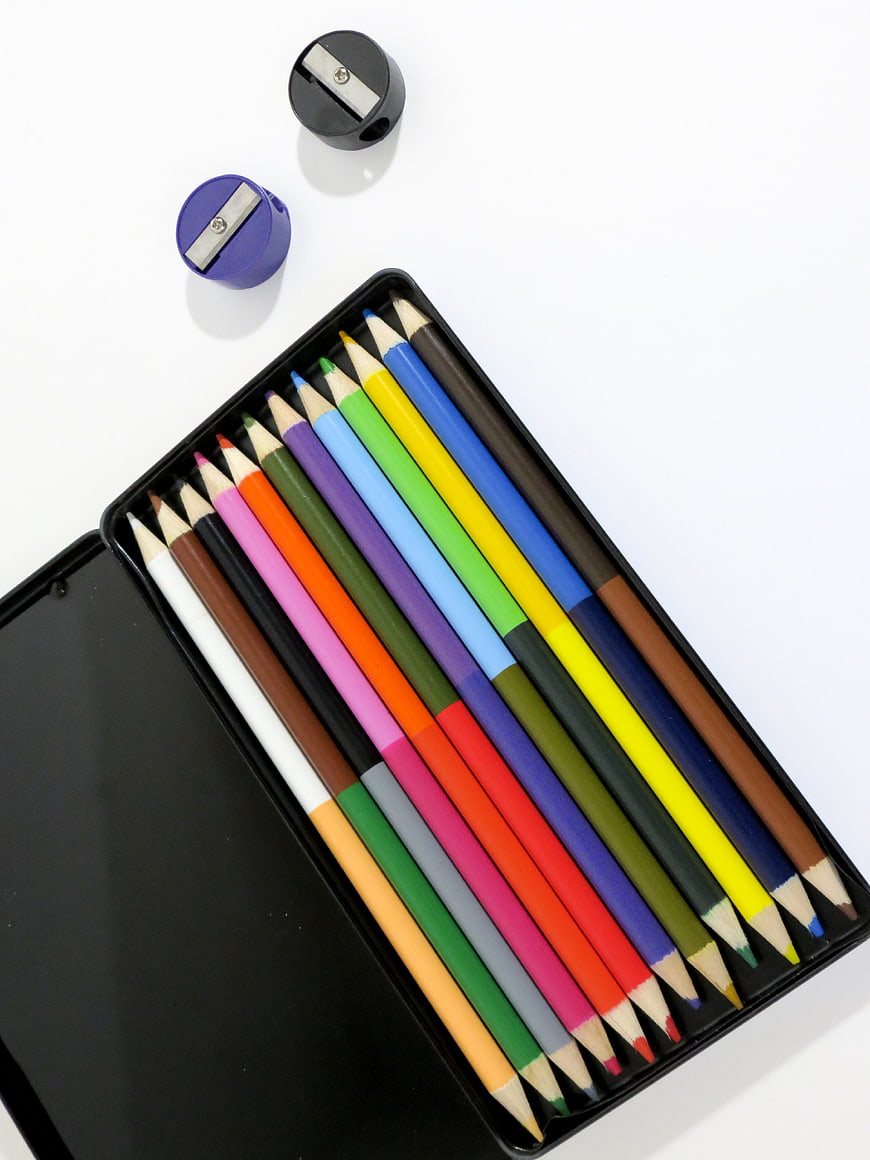 Flat lay of colorful pencils in a black tin box with sharpeners