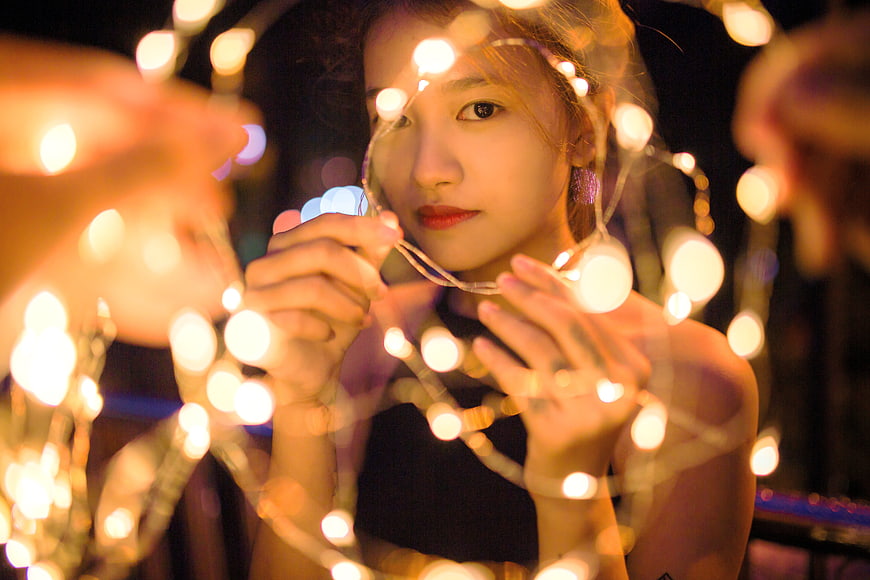 Woman holding glowing fairy lights at night