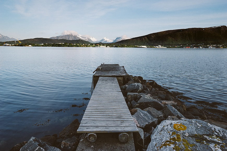 Wooden Dock Leading to Calm Water with Mountains