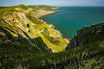 Scenic coastal cliffs with green grass and turquoise ocean view