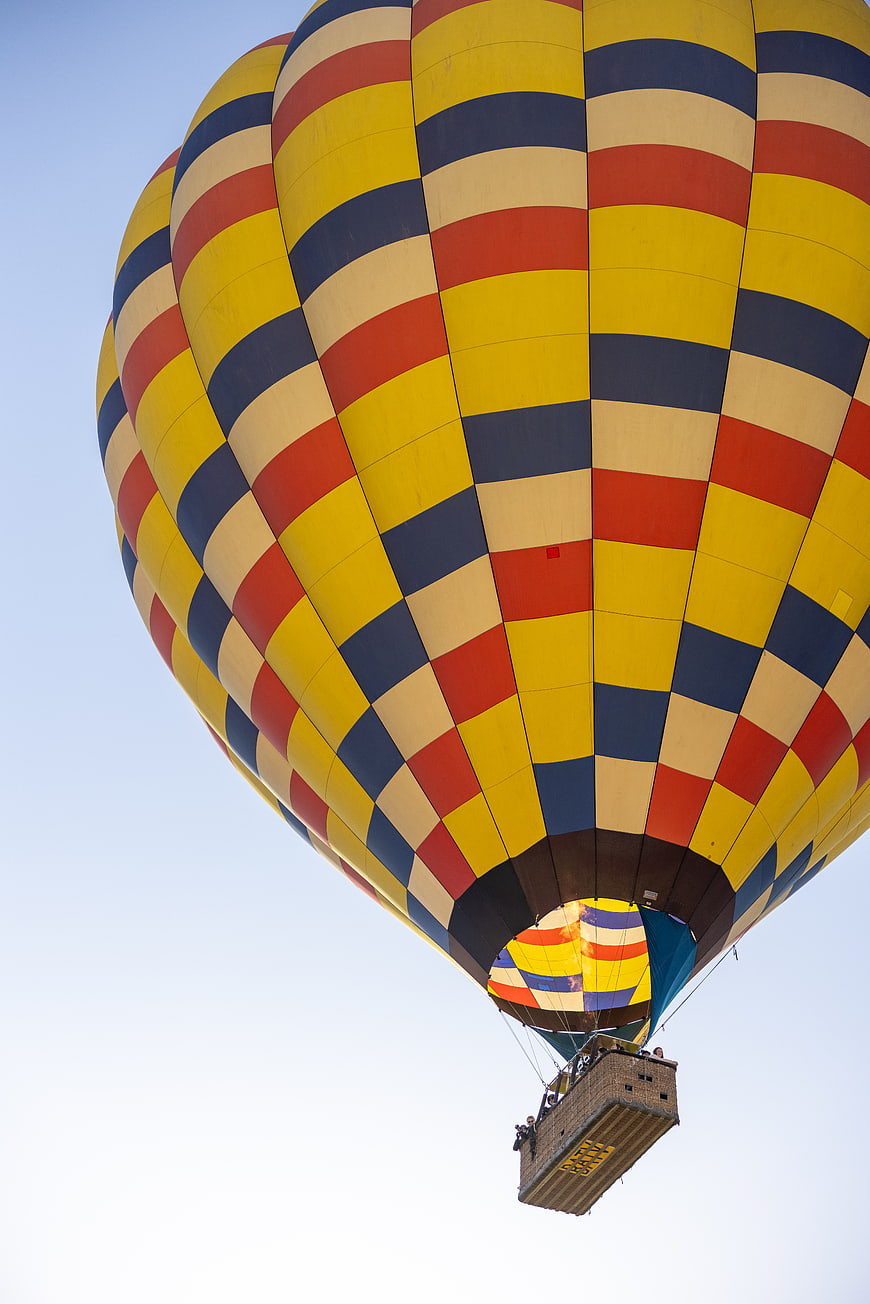 Colorful Striped Hot Air Balloon Flying in Blue Sky