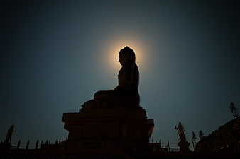 Silhouette of Buddha Statue Backlit by Moonlight